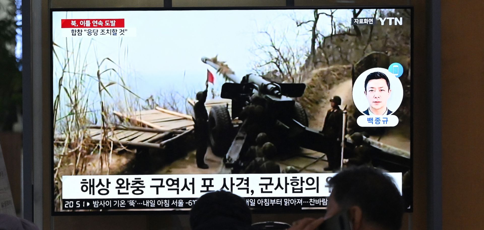 People watch a television screen showing a news broadcast with file footage of North Korea's artillery firing, at a railway station in Seoul on Jan. 6, 2024.