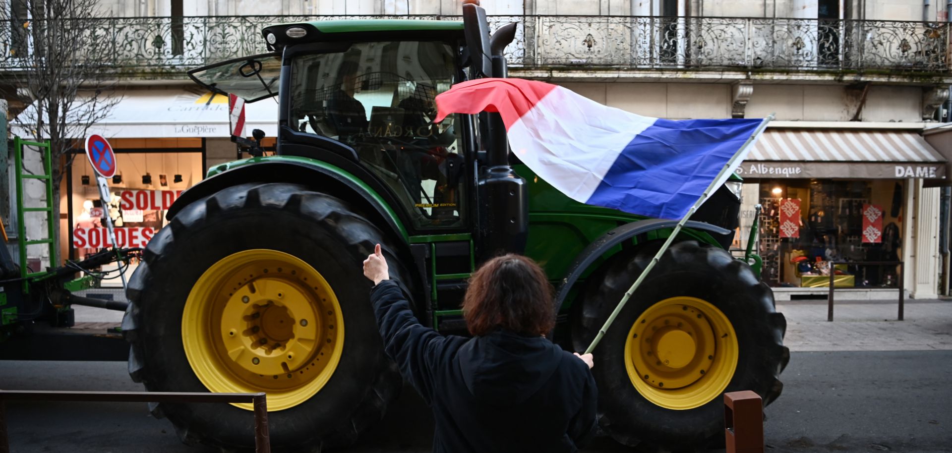A woman waves a French flag in support of protesting farmers as a tractor drives by in Agen, southwerstern France, on Jan. 25, 2024.