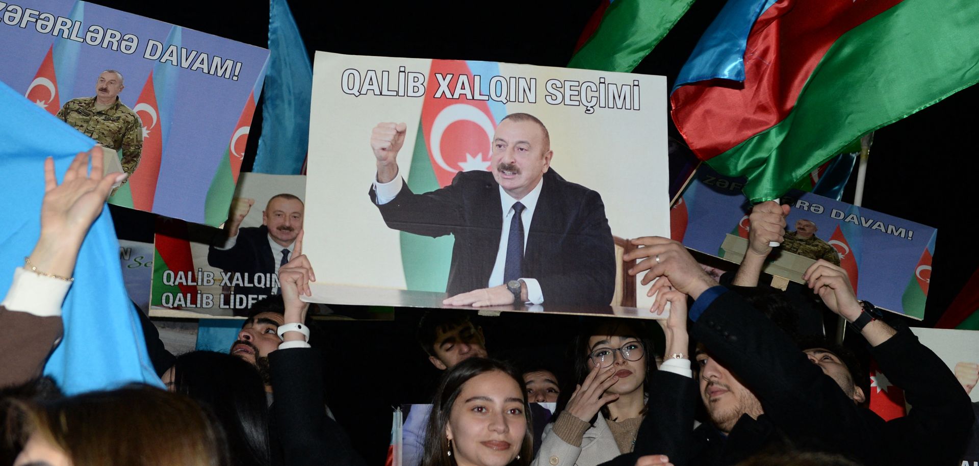 Supporters of Azerbaijani President Ilham Aliyev rally with national flags and his portraits in Baku, Azerbaijan, after polls closed in the country's snap presidential election on Feb. 7, 2024. 