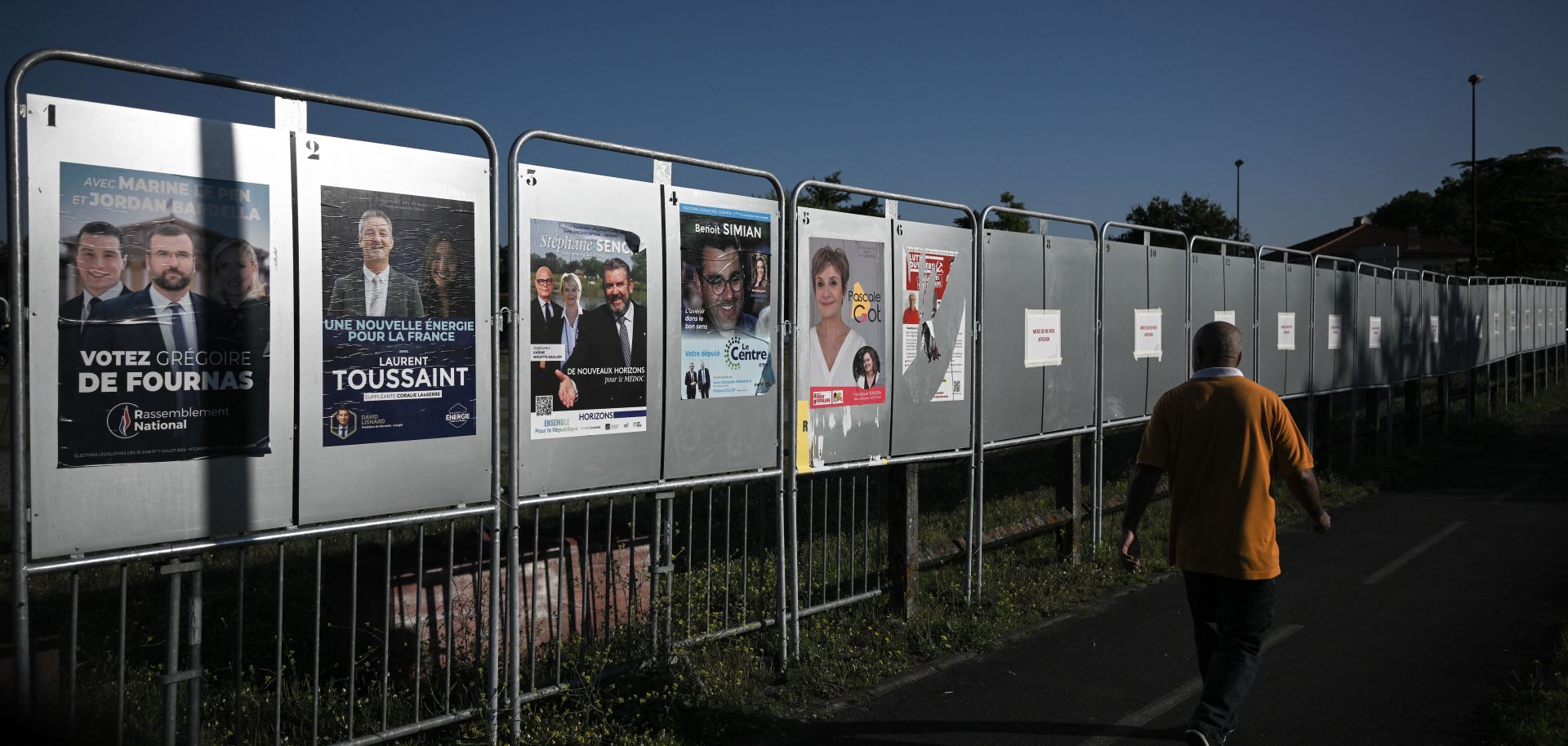 A man walks past campaign posters for France's upcoming legislative elections in Parempuyre, southwestern France, on June 25, 2024.