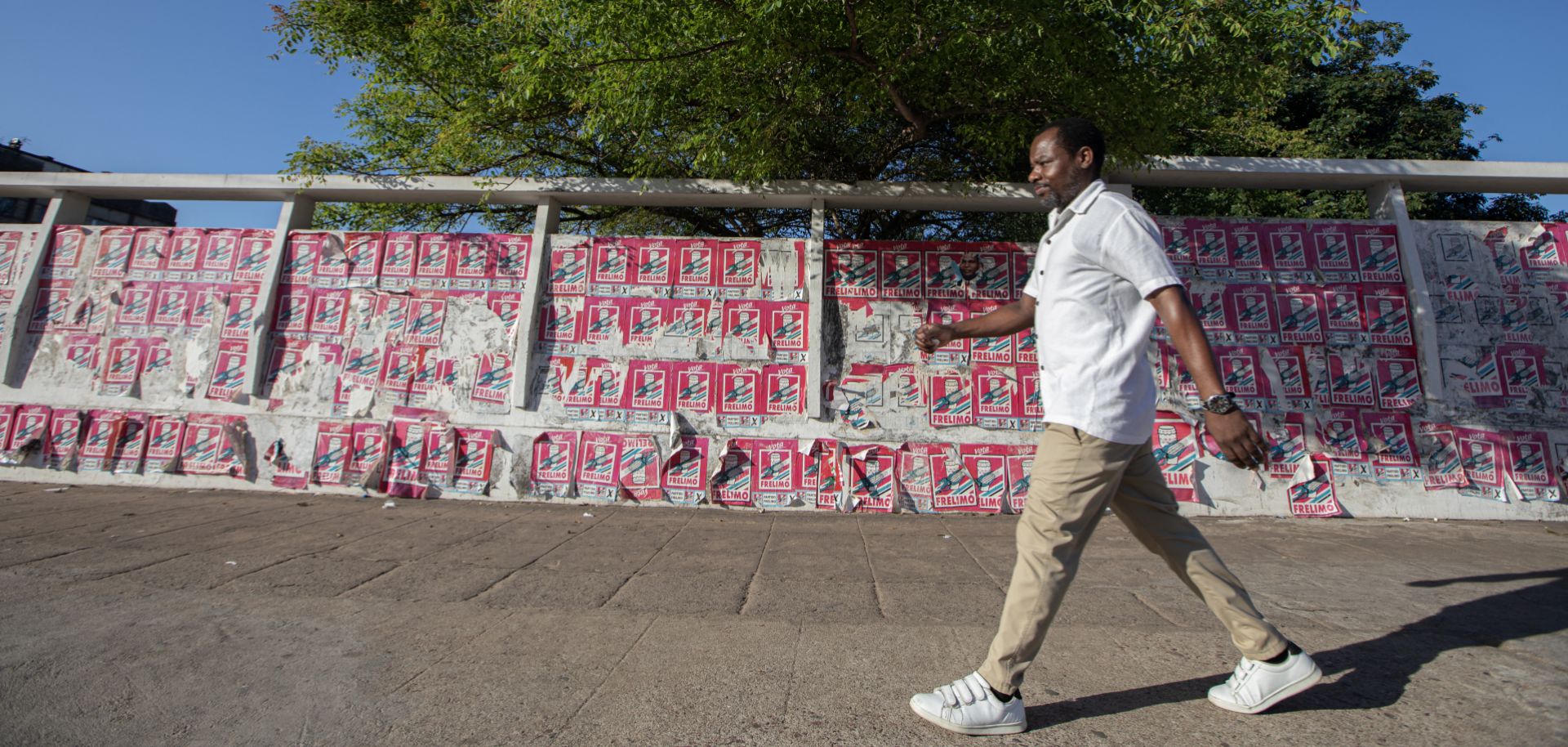 A man in Maputo walks past a wall covered with electoral posters in support of Daniel Chapo, the ruling party candidate in Mozambique’s presidential election, on Oct. 4, 2024. 