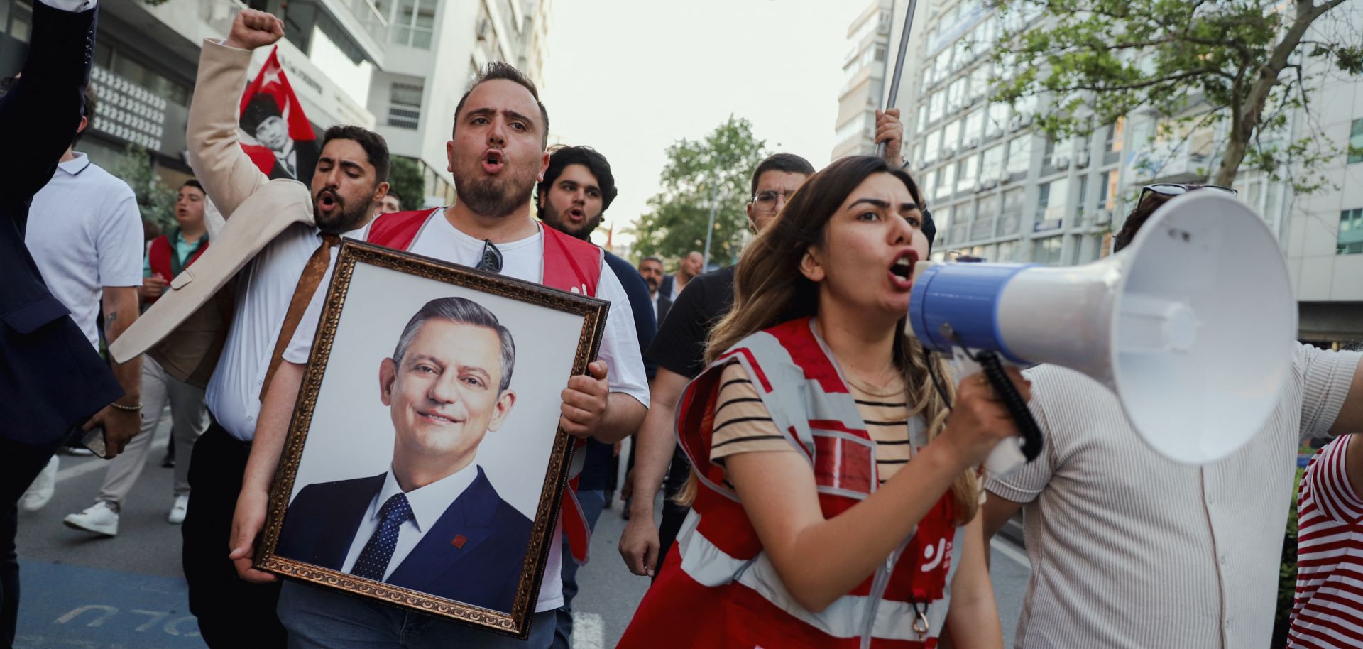 Demonstrators yell through a megaphone and hold a framed portrait of the ousted Republican People's Party (CHP) chairman, Ogur Ozel, during an opposition rally in Izmir, Turkey, on May 24, 2026. 