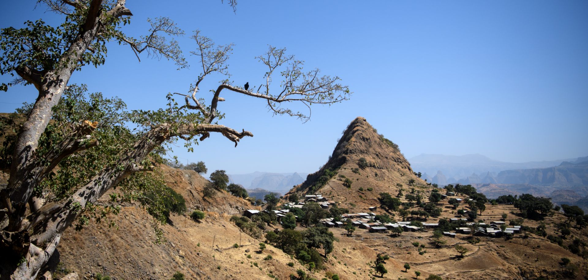 A photograph shows a village below a prominent hill in the Semien Mountains near Gondar, Ethiopia.