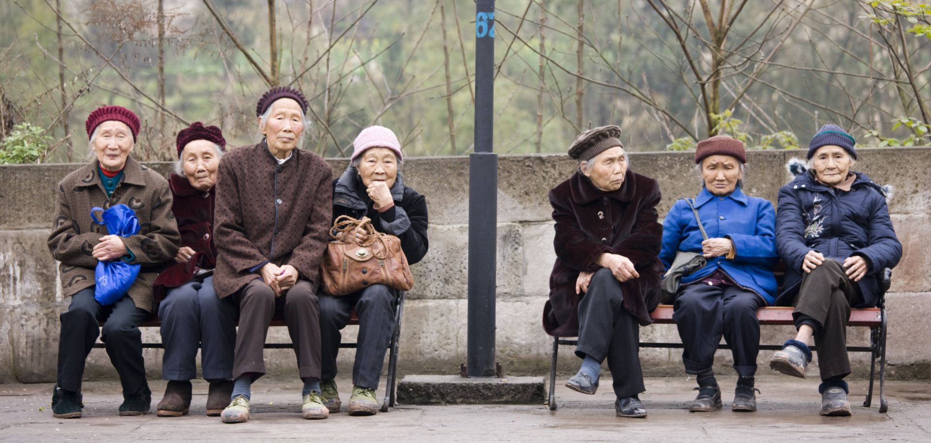 Elderly women sit together on benches in Chongqing, China.