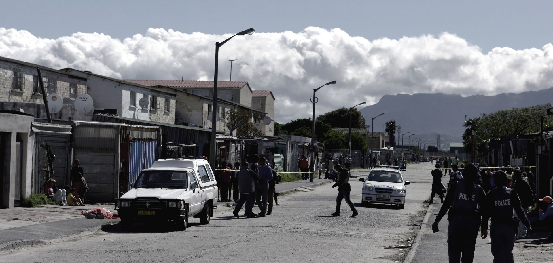 Residents gather as South African police officers respond to a shooting of two alleged gang members in Cape Town in 2017.