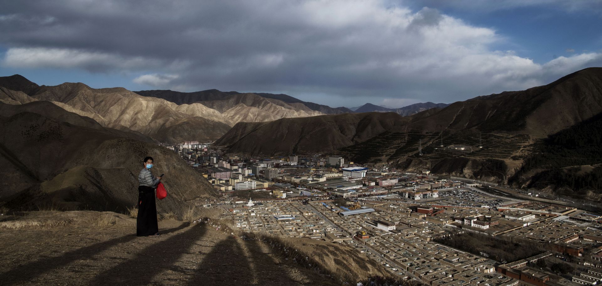 A Tibetan Buddhist woman stands on a hill overlooking the Labrang Monastery on March 2, 2018, in Gansu, China, the country's poorest province.