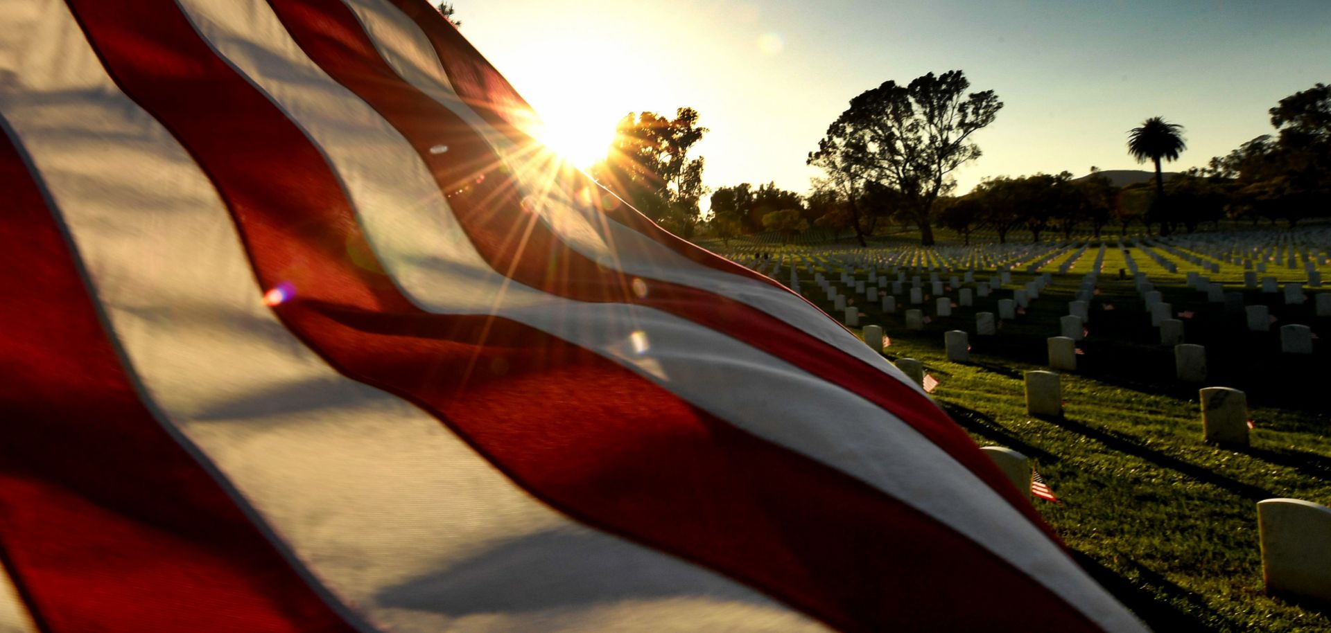 The sun sets over a U.S. flag at a veterans cemetery in Los Angeles, California, in May 2018.