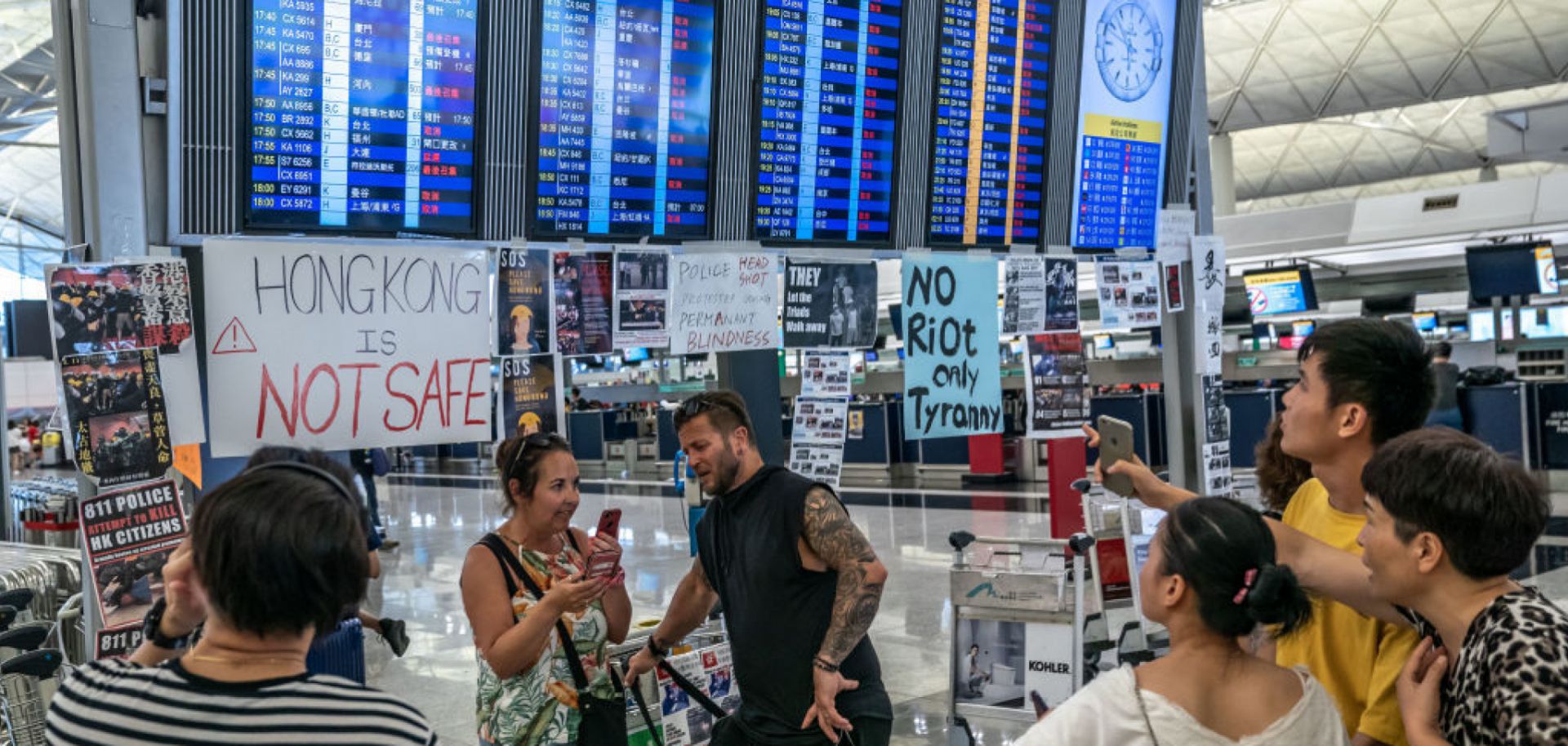 Tourists look at the information panel that shows all flights are canceled at Hong Kong International Airport during a demonstration on Aug. 12, 2019, in Hong Kong.