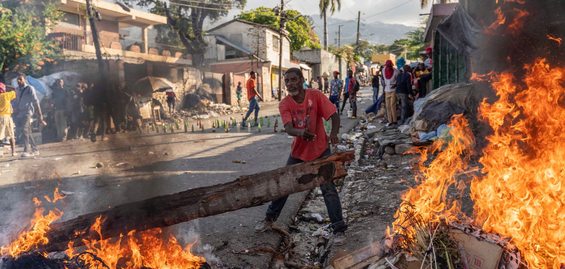 A man adds wood to a fire burning in the streets of Port-au-Prince, Haiti, on Oct. 3 amid protests demanding the resignation of Haitian Prime Minister Ariel Henry. 