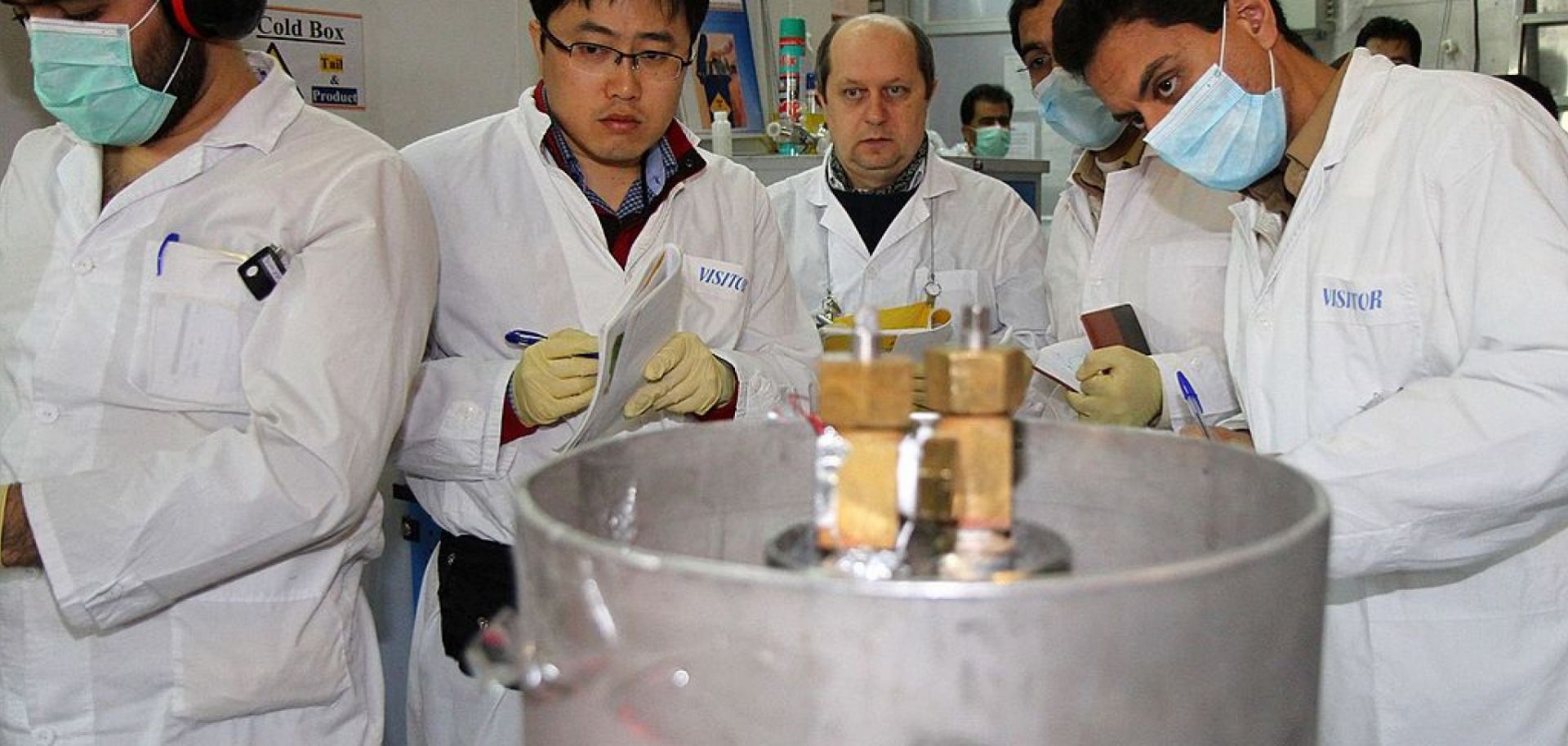 IAEA inspectors (2nd, 3rd L) and Iranian technicians disconnect the connections between the twin cascades for 20 percent uranium production at nuclear power plant of Natanz, Iran, on Jan., 20, 2014.