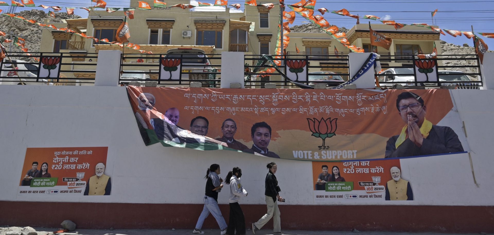 People walk past campaign posters for the ruling Bharatiya Janata Party (BJP) outside the party's office in Leh, India, on May 17, 2024, during the country's ongoing general election.