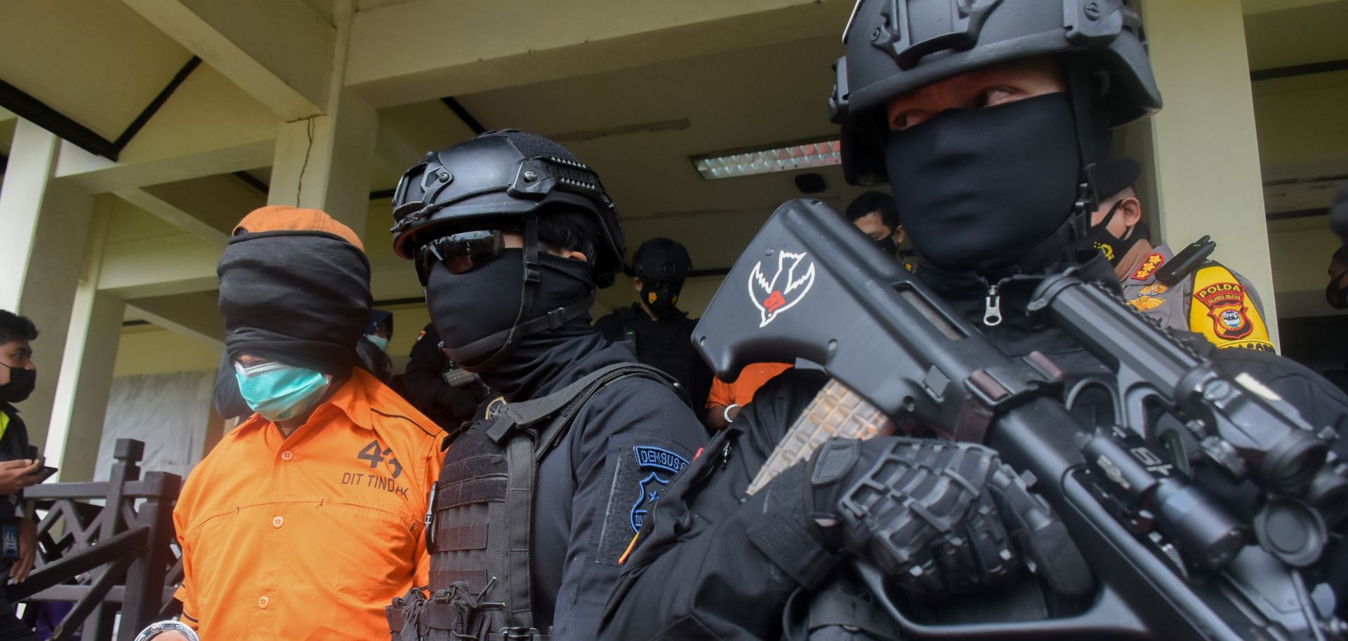 Police escort one of 19 terror suspects being transferred to Jakarta fro Makassar on Feb. 4, 2021, at Sultan Hasanuddin International Airport in Makassar, Indonesia.