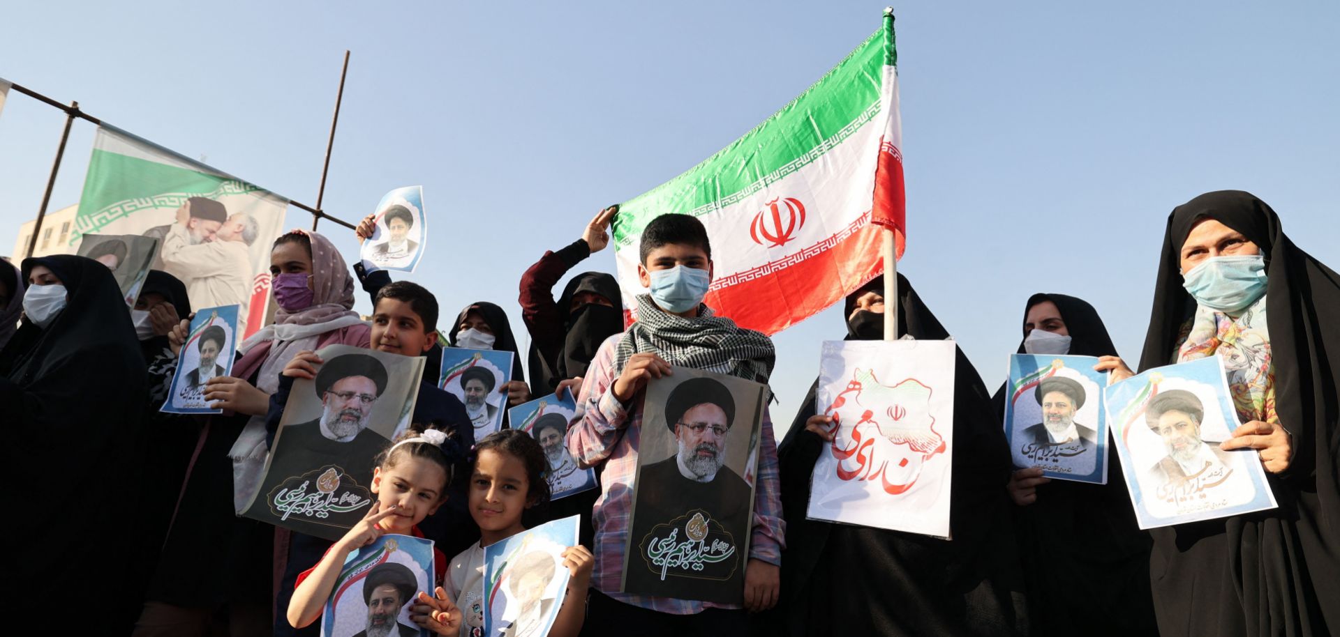 Supporters of Iranian presidential candidate Ebrahim Raisi hold campaign posters at a rally in Tehran on June 14, 2021. 