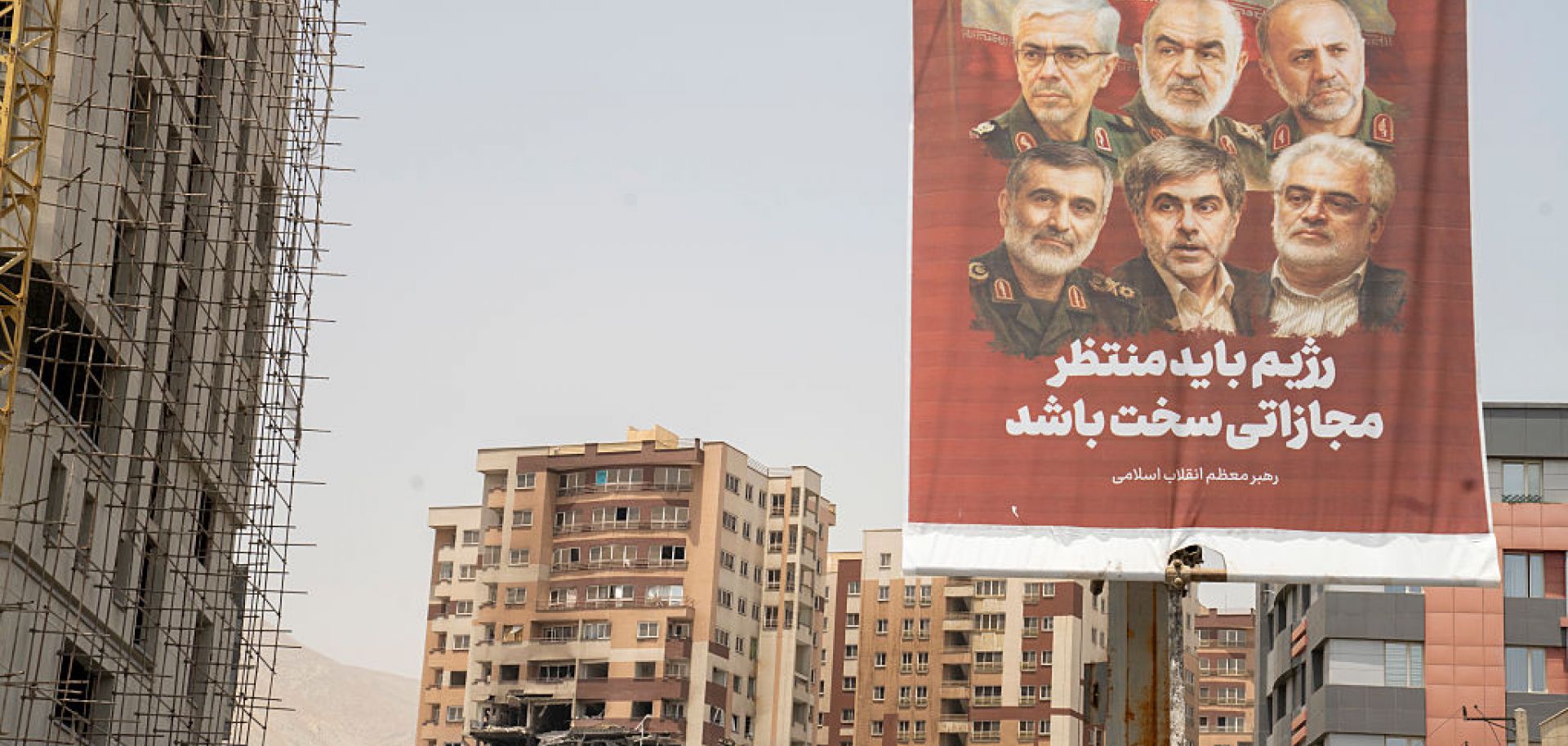 A photo taken in Tehran, Iran, on June 26, 2025, shows an Iranian political banner hanging near the remains of a residential building struck by an Israeli attack.