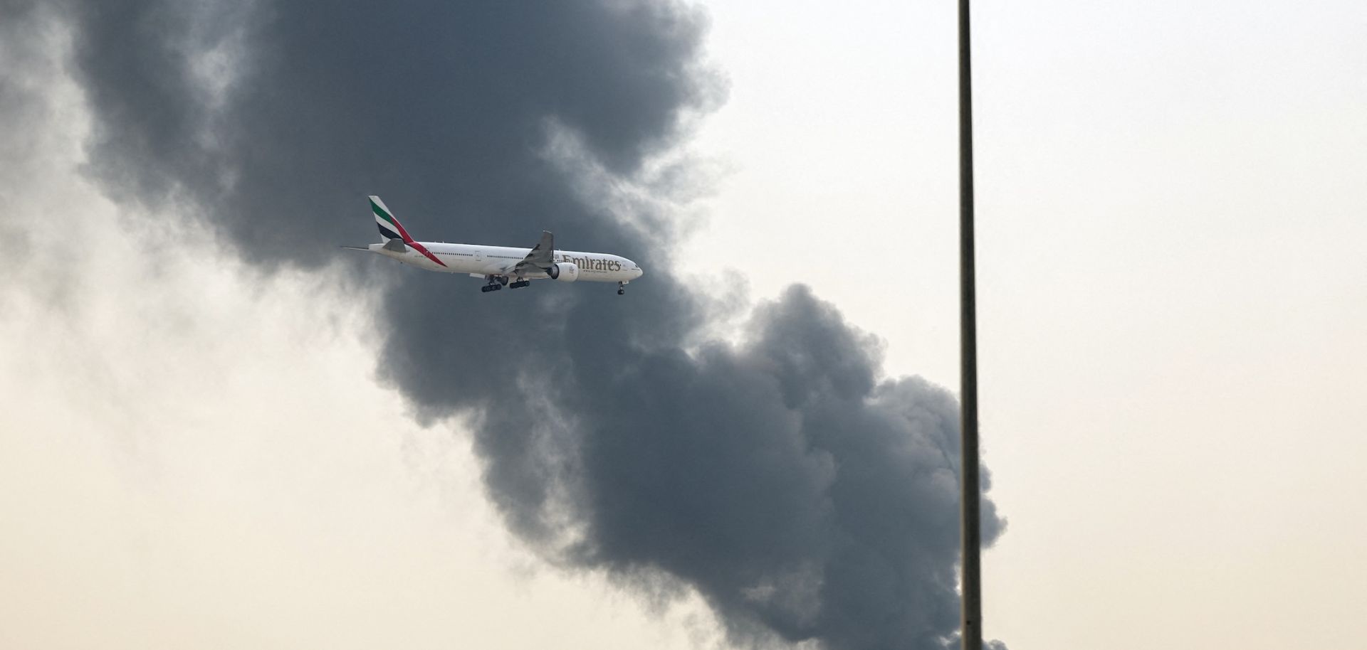 An Emirates Boeing 777 aircraft prepares for landing as a smoke plume rises from an ongoing fire near Dubai International Airport in Dubai on March 16.