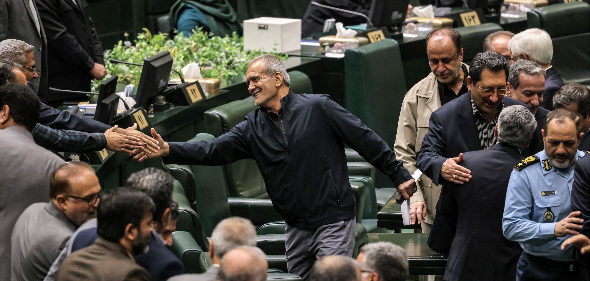 Iran's President Masoud Pezeshkian (C) greets parliament members after giving an address during a session to approve his new Cabinet appointments in Tehran on Aug. 21, 2024.