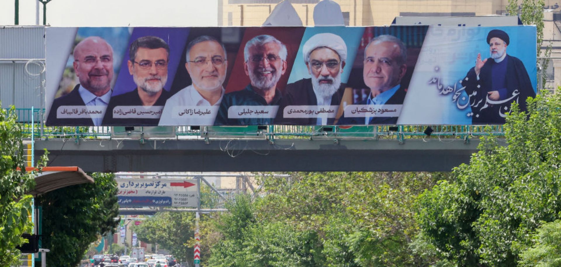 A billboard displaying the faces of the six candidates in Iran's 2024 presidential election with July 5 runoff winner Masoud Pezeshkian at second from right.