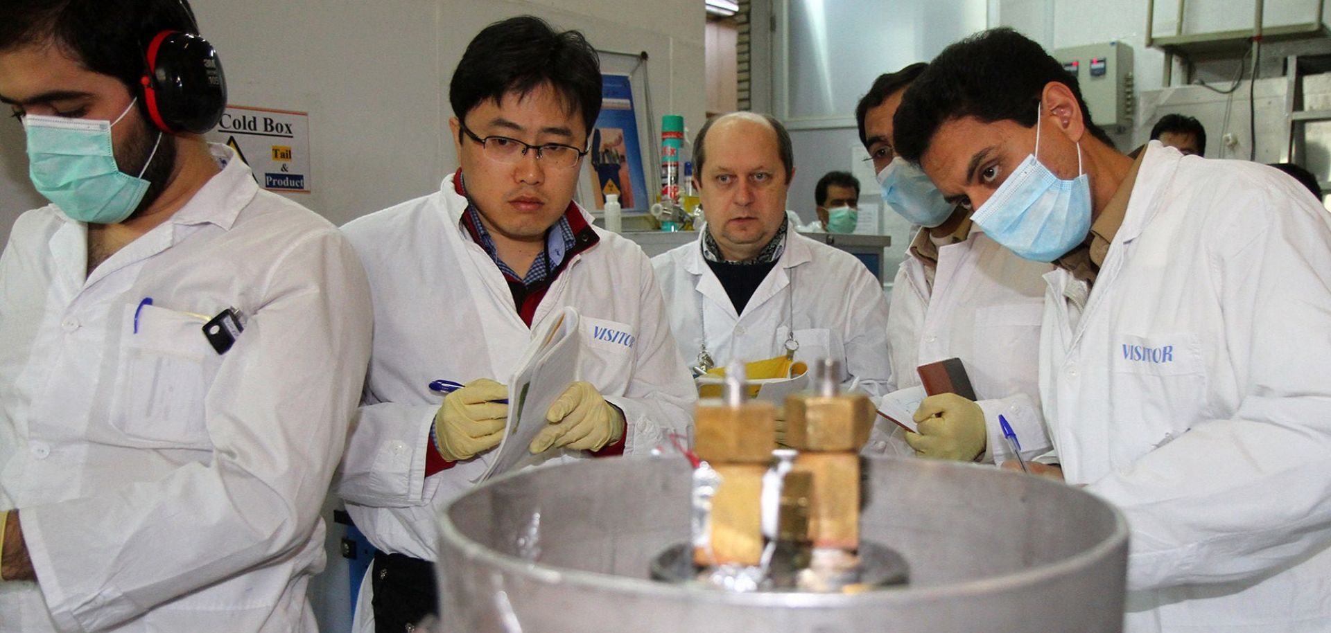 Two inspectors with the International Atomic Energy Agency, second and third from left, observe Iranian technicians stop the production of 20 percent enriched uranium at the Natanz nuclear facility on Jan. 20, 2014.