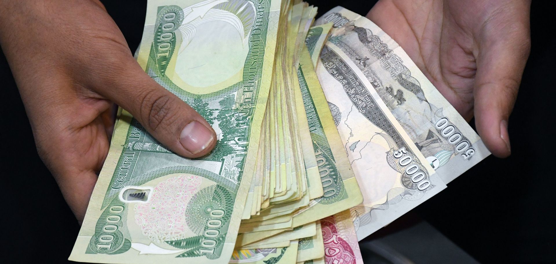 An employee of a currency exchange counter shows a stack of local currency bank notes in the southern Iraqi city of Nasiriyah in Dhi Qar province on Dec. 20, 2020.