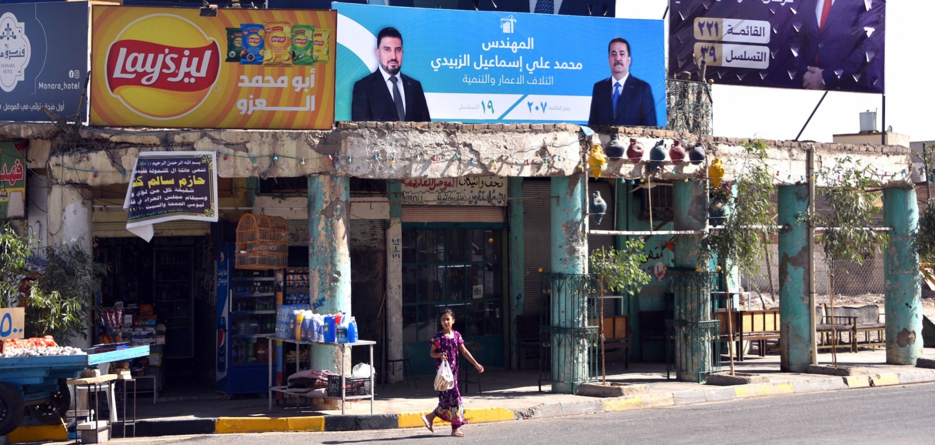 A girl walks past posters and banners depicting political candidates from rival blocs competing for a seat in the Iraqi Council of Representatives in old Mosul, northern Iraq, on Oct. 28, 2025, days before the Nov. 11, 2025, parliamentary elections.