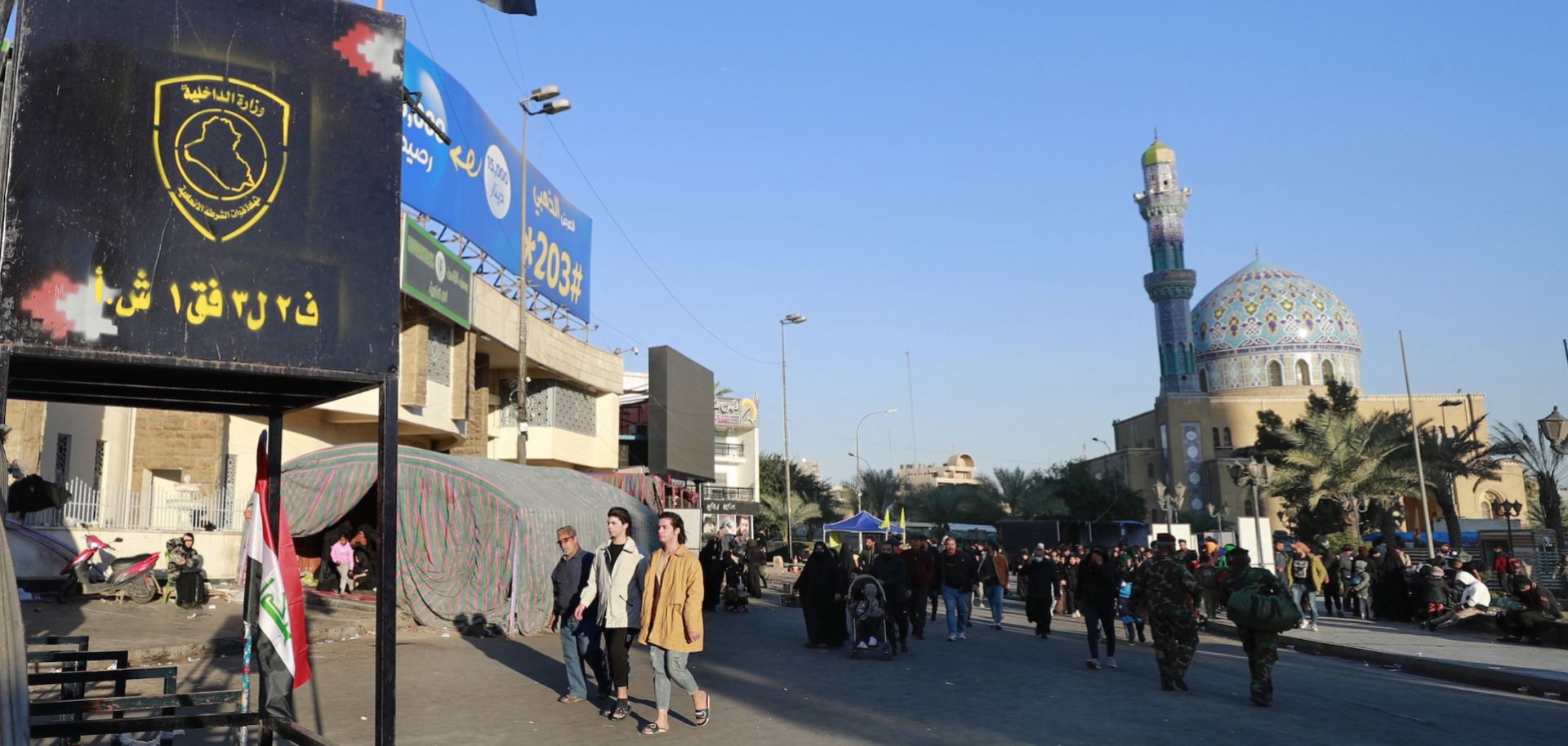 A member of the Iraqi security forces stands guard next to a national flag as pilgrims march from the center of Baghdad toward the shrine of Imam Moussa al-Kadhim, the seventh of 12 revered imams in Shiite Islam, during an annual religious commemoration on Feb. 16, 2023.