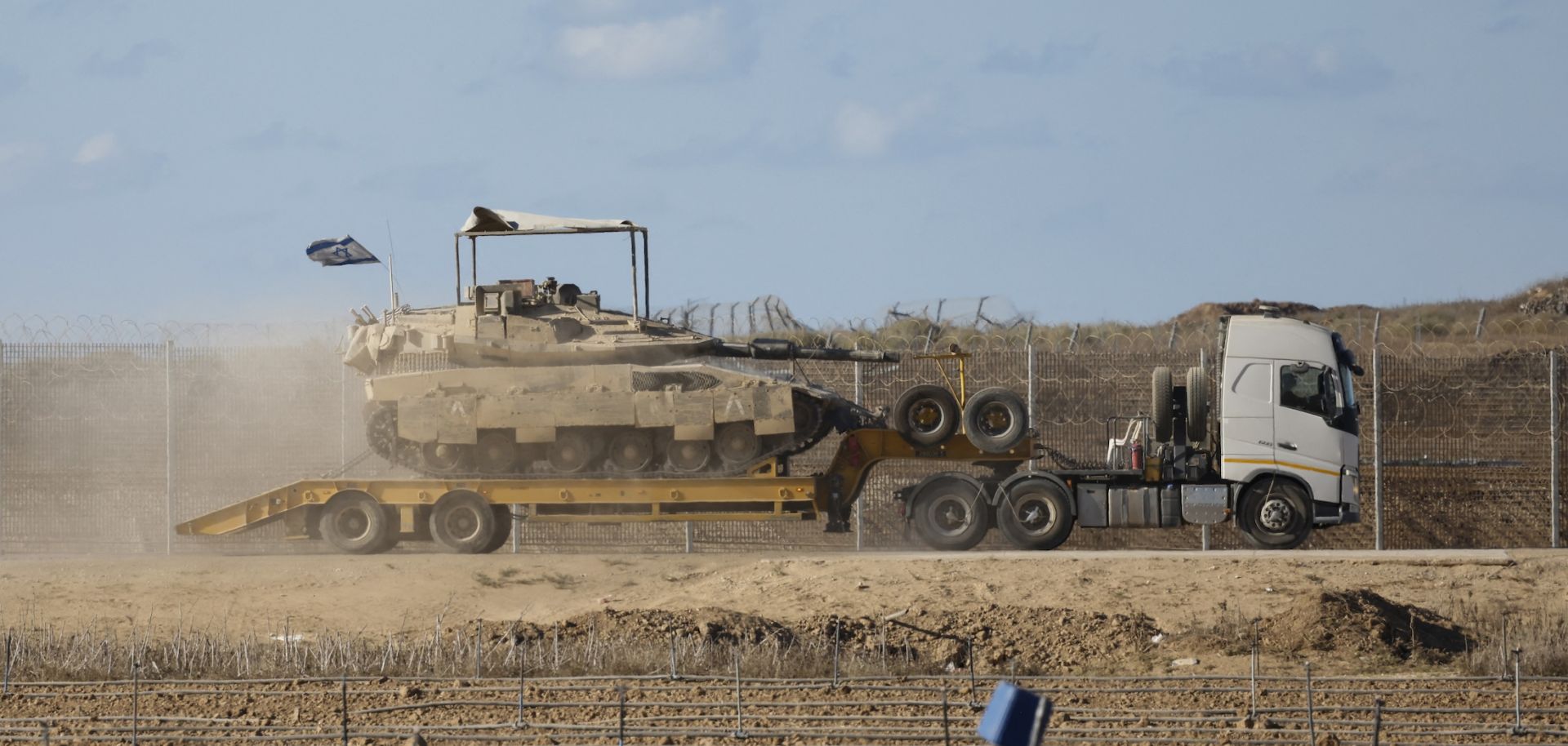 An Israeli military truck carries a tank in southern Israel on the border with the Gaza Strip, on Oct. 14, 2025.