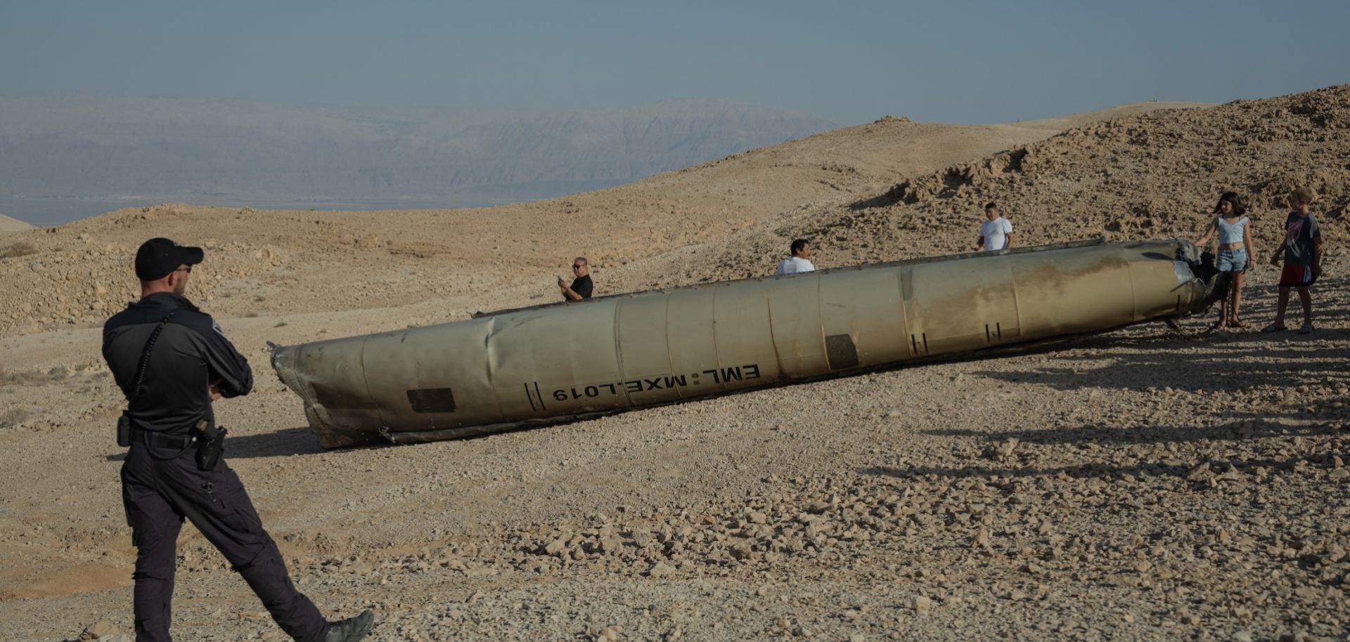 An Israeli police officer stands near the remains of an Iranian missile on Oct. 2, 2024, near the Dead Sea, Israel. 