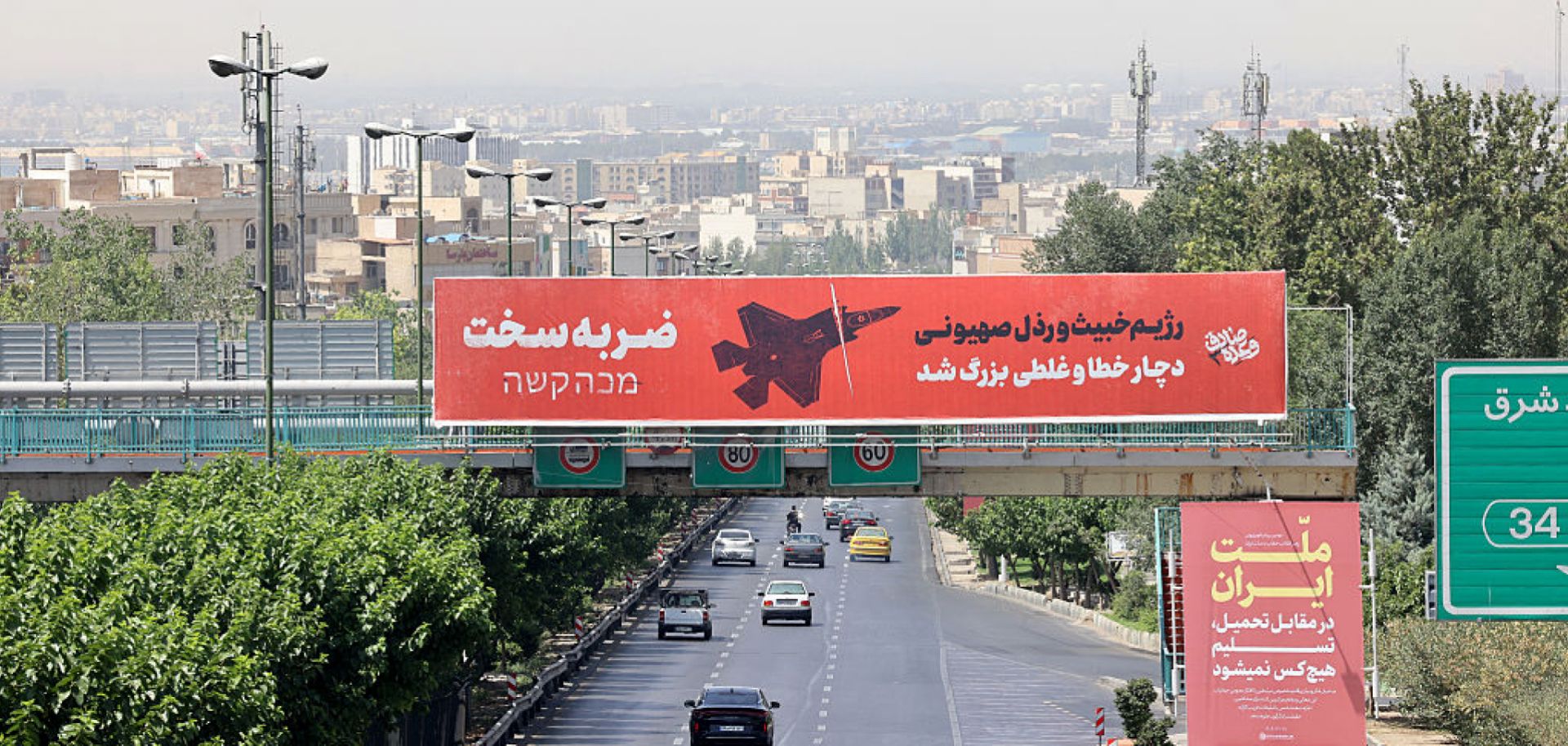 Vehicles drive along a main thoroughfare past a billboard that reads in Farsi and Hebrew: "A severe blow... The vile and villainous Zionist regime (Israel) has made a grave mistake,” in central Tehran on June 24, 2025.