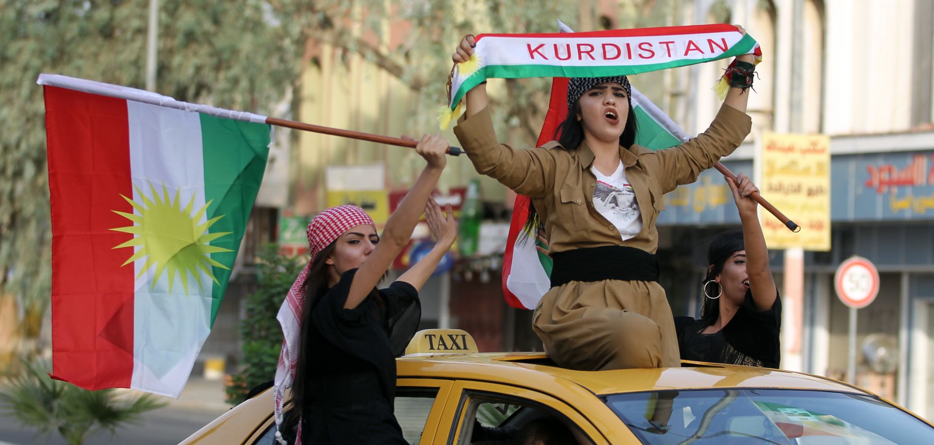 Iraqis Kurdish women celebrate with the Kurdish flag as they ride outside the windows and roof of a taxi in the northern city of Kirkuk, Sept. 25.