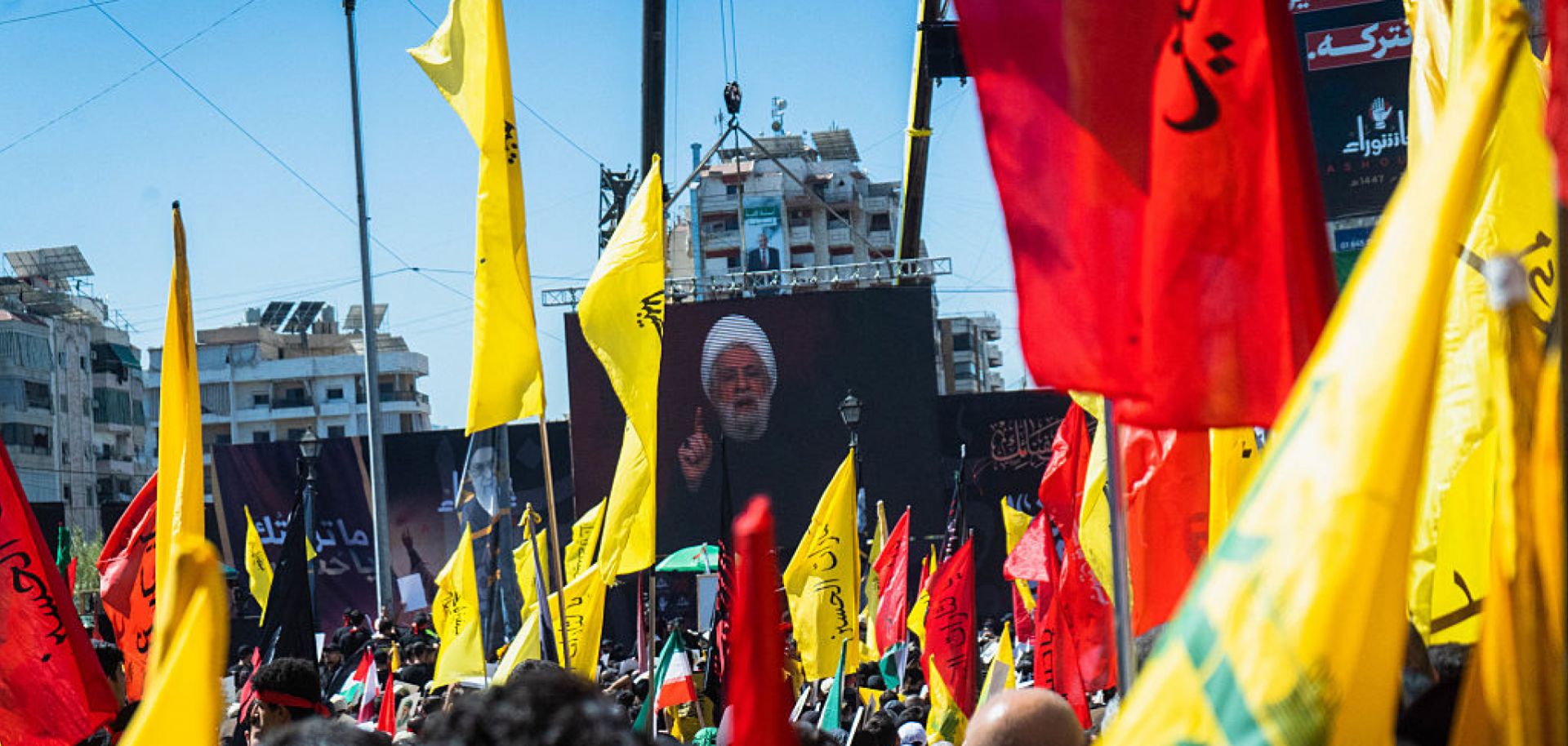 Hezbollah leader Naim Kassem speaks from a stage surrounded by flags in the southern suburbs of Beirut, Lebanon, on July 6, 2025. 
