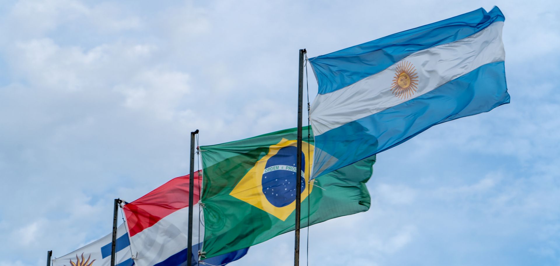 A photo shows the national flags of Mercosur countries waving in the wind.