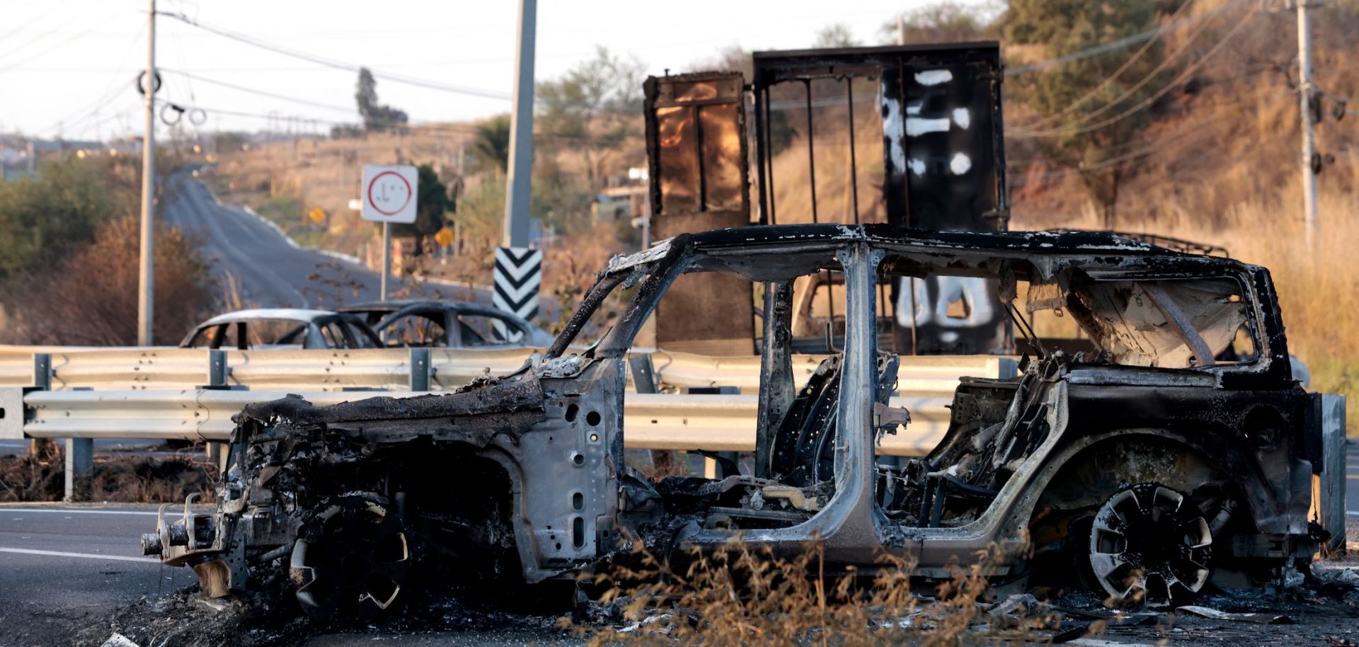 A burned car is seen on a highway near Acatlan de Juarez, Jalisco state, Mexico, on Feb. 22, 2026. The car was allegedly set on fire by organized crime groups in response to the killing of Nemesio Oseguera "El Mencho," the top leader of the Jalisco New Generation Cartel (CJNG).