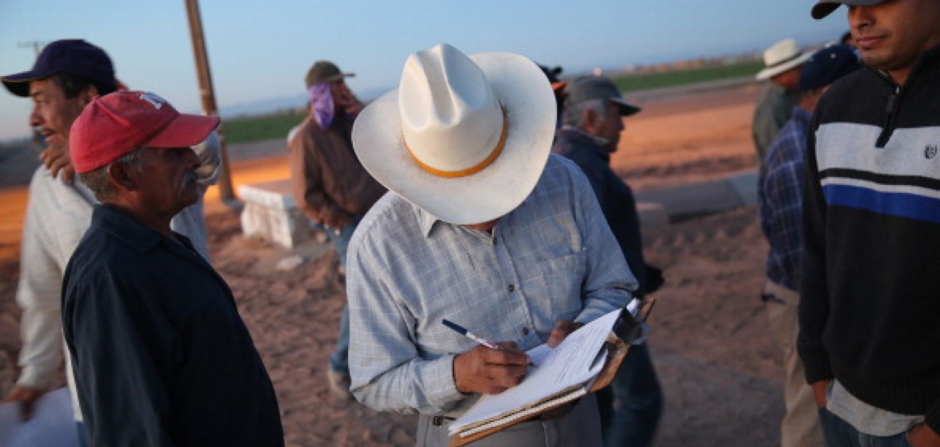 Mexican agricultural day laborers sign their names to a list before starting work on October 8, 2013 in Holtville, California.