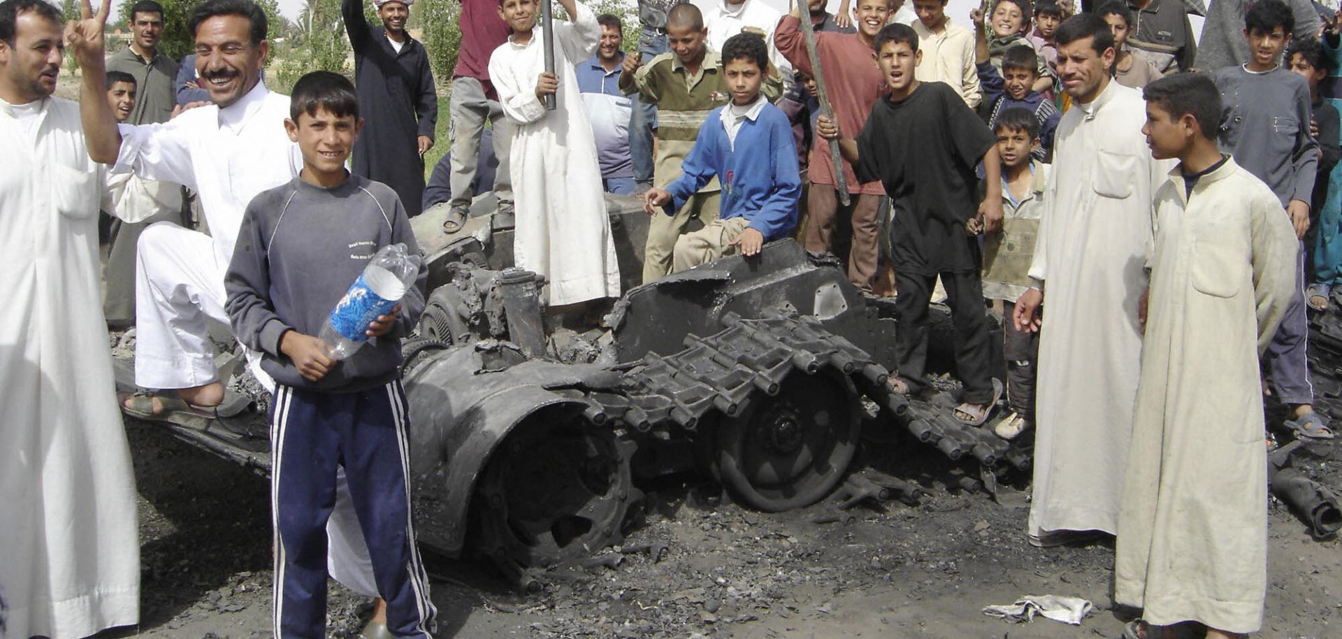 Iraqis pose with the remnants of what they say is a destroyed U.S. military vehicle that was part of "Operation Matador" in Karbala, near the Iraqi-Syrian border.