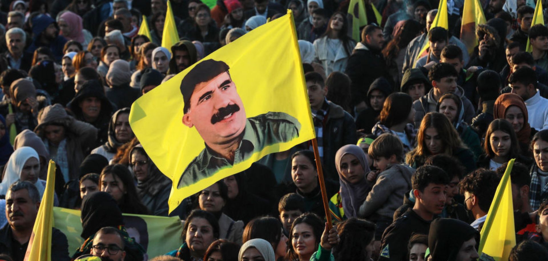A Syrian Kurdish woman waves a flag bearing a picture of the founder of the Kurdistan Workers' Party (PKK), Abdullah Ocalan, as people gather in the Kurdish-majority city of Qamishli in northeastern Syria to listen to a message from the jailed leader on Feb. 27, 2025. 