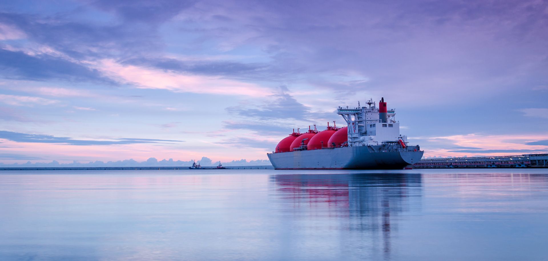 The sun rises over an LNG terminal at sea.