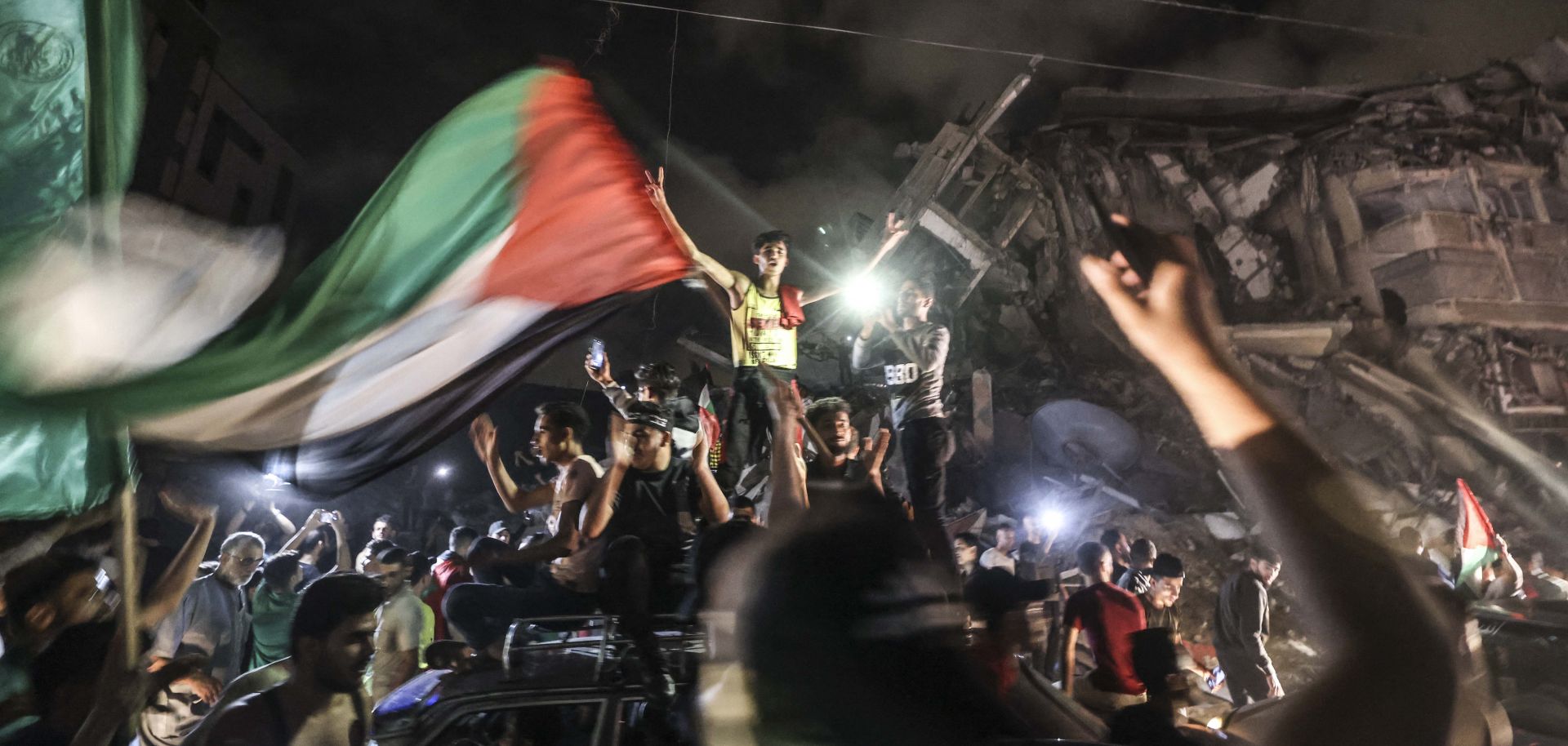 People in Gaza City wave the Palestinian flag in celebration of the cease-fire reached between Israel and Hamas on May 21, 2021.