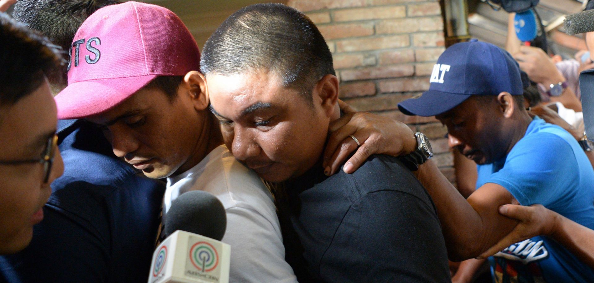 Jaypee Gordiones, Felix Dela Torre and Richard Blaze (left to right), crew members of a fishing vessel that sank after it collided with a Chinese fishing boat off Reed Bank in the South China Sea, are mobbed by journalists following a news conference in Manila on June 28, 2019.