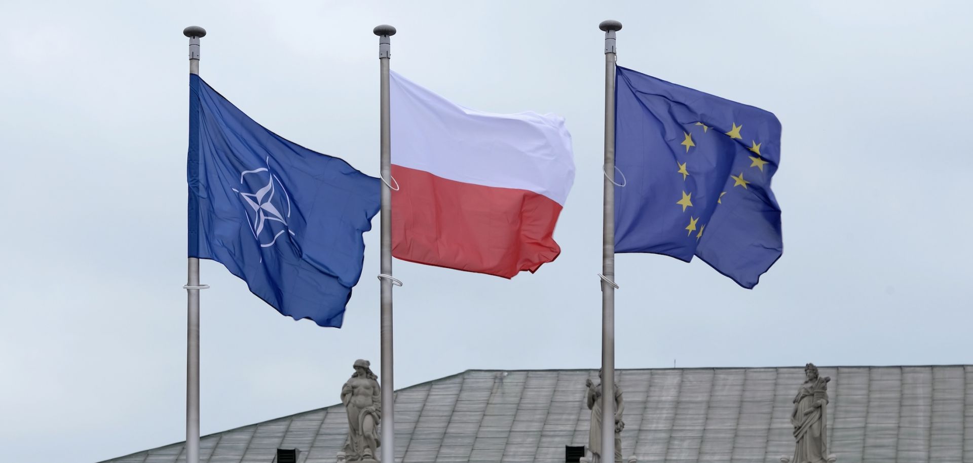The flags of NATO, the EU and Poland are seen next to each other. 