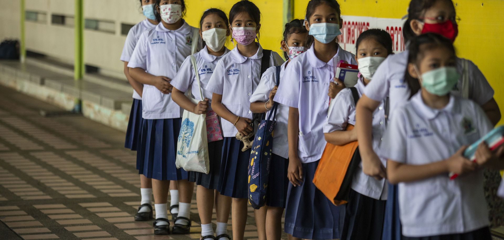  Thai students wear face mask as they stand in line to enter their classroom at the Thai Niyom Songkhrao School