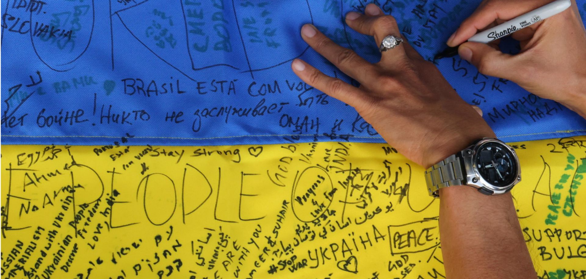 A woman signs a Ukranian flag at the Ukraine Pavillion Expo 2020 in Dubai