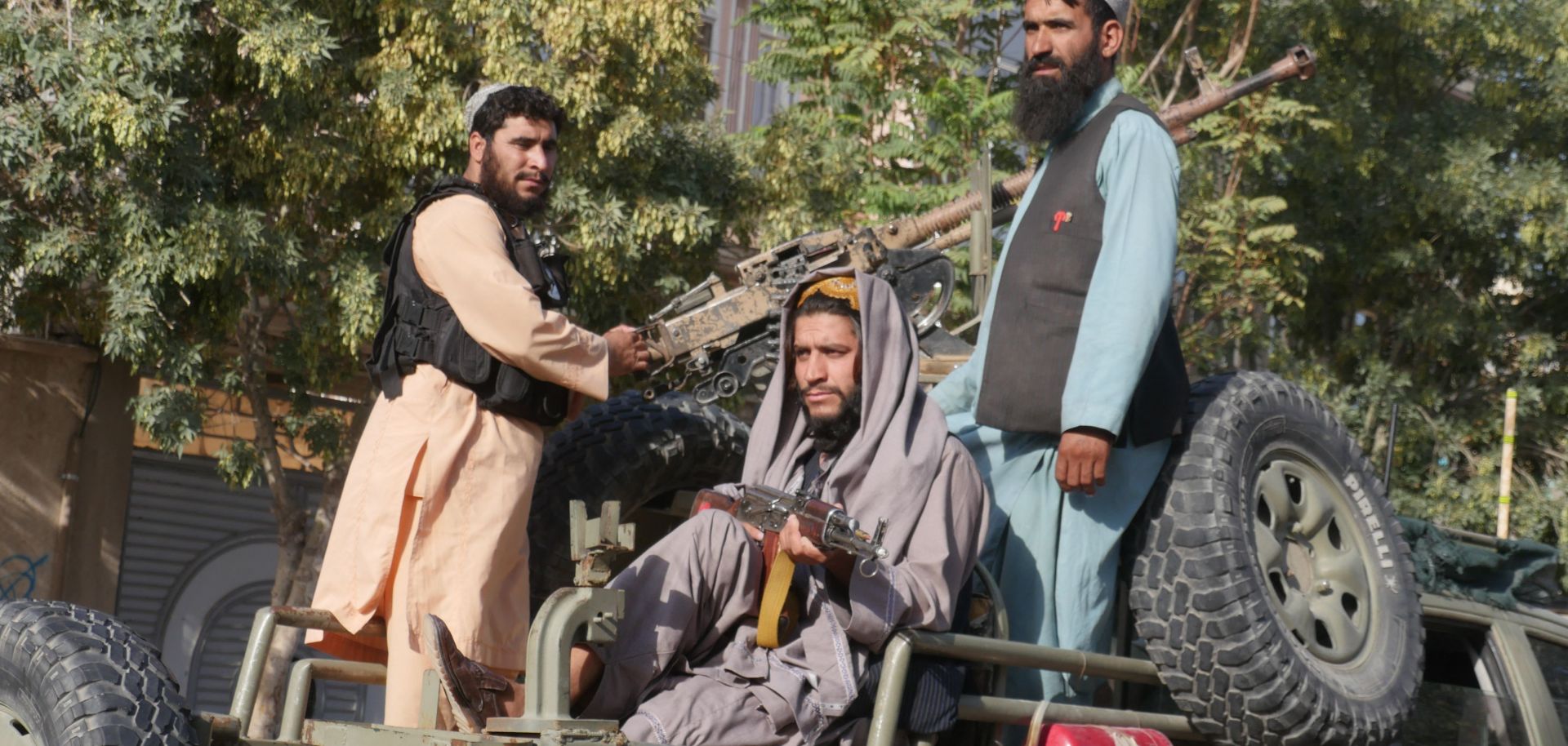  Taliban fighters stand on the back of a vehicle