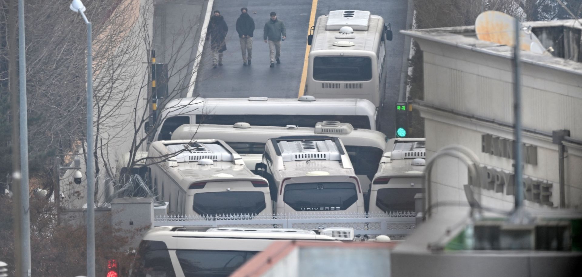 Security personnel walk on a road with buses blocking an entrance gate to protect impeached South Korean President Yoon Suk Yeol from a possible second arrest in Seoul on Jan. 6.