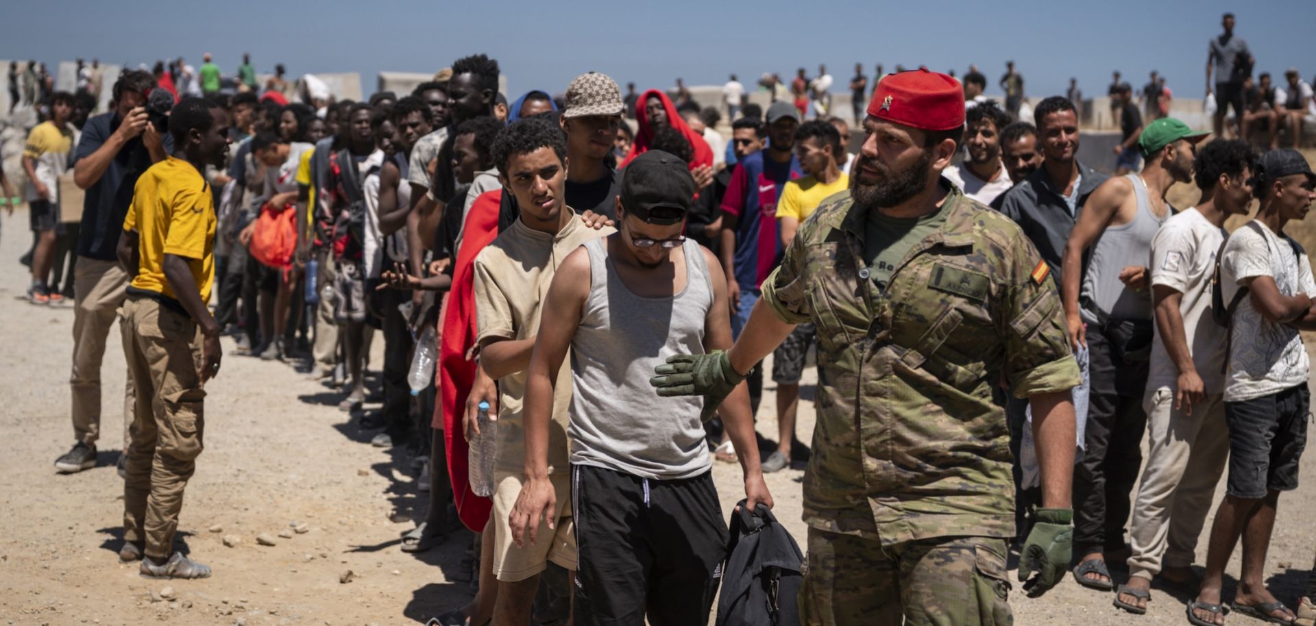 Migrants wait to receive water on a beach in the North African Spanish enclave of Ceuta on Aug. 2, 2026.
