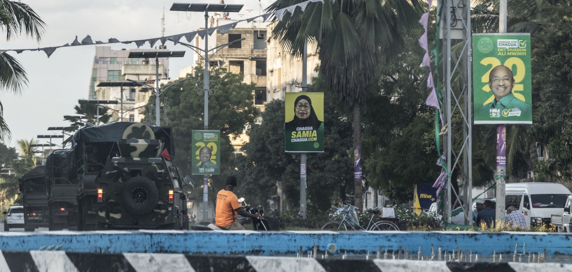 A column of Tanzanian soldiers drives past electoral posters of incumbent Tanzanian President Samia Suluhu Hassan and Zanzibar President Hussein Ali Mwinyi in Stone Town on Oct. 30, 2025. 