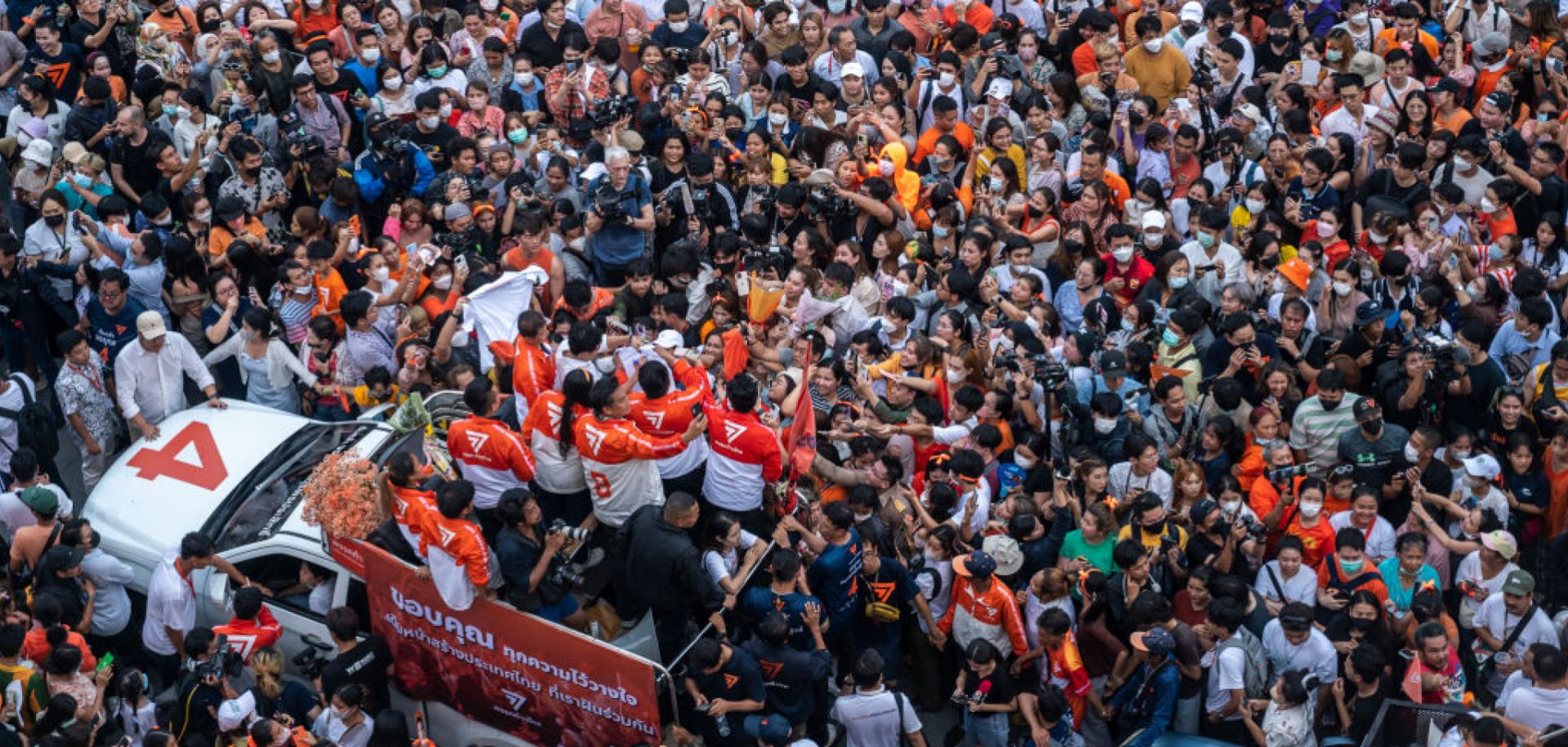 A car with members of Thailand's opposition Move Forward Party (MFP), including leader Pita Limjaroenrat, drives through a large crowd of supporters during a rally in Bangkok on May 15, 2023, following the MFP's victory in the general election.
