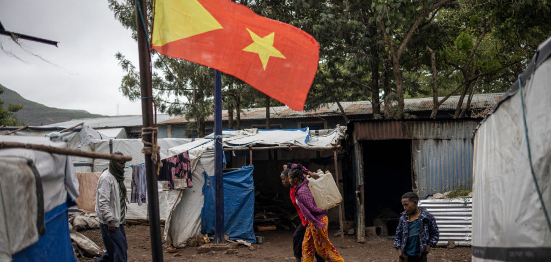 Internally displaced people walk past the Tigrayan flag at the Tsehaye camp in Ethiopia's Shire, Tigray region, on July 16, 2024. 