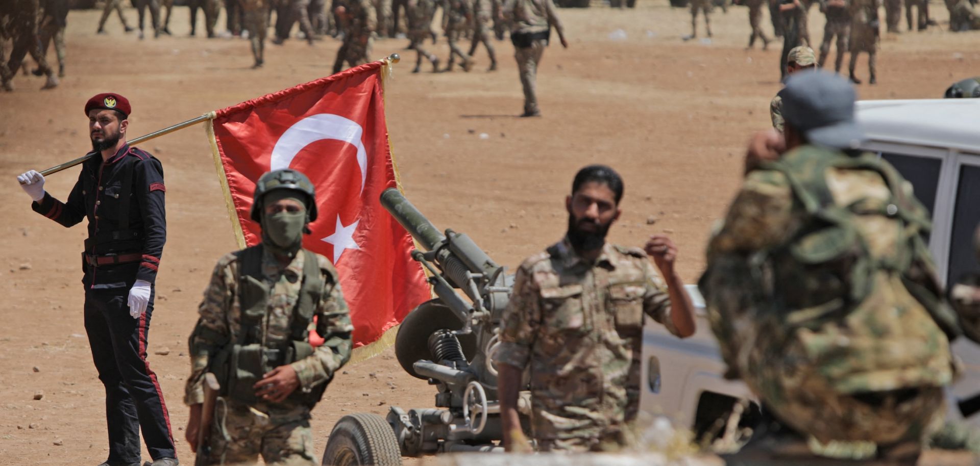 A man carries a Turkish national flag as Turkey-backed Syrian fighters gather along the frontlines opposite Kurdish forces near the town of Dadat in Syria's northern Aleppo province, on July 5, 2022. 