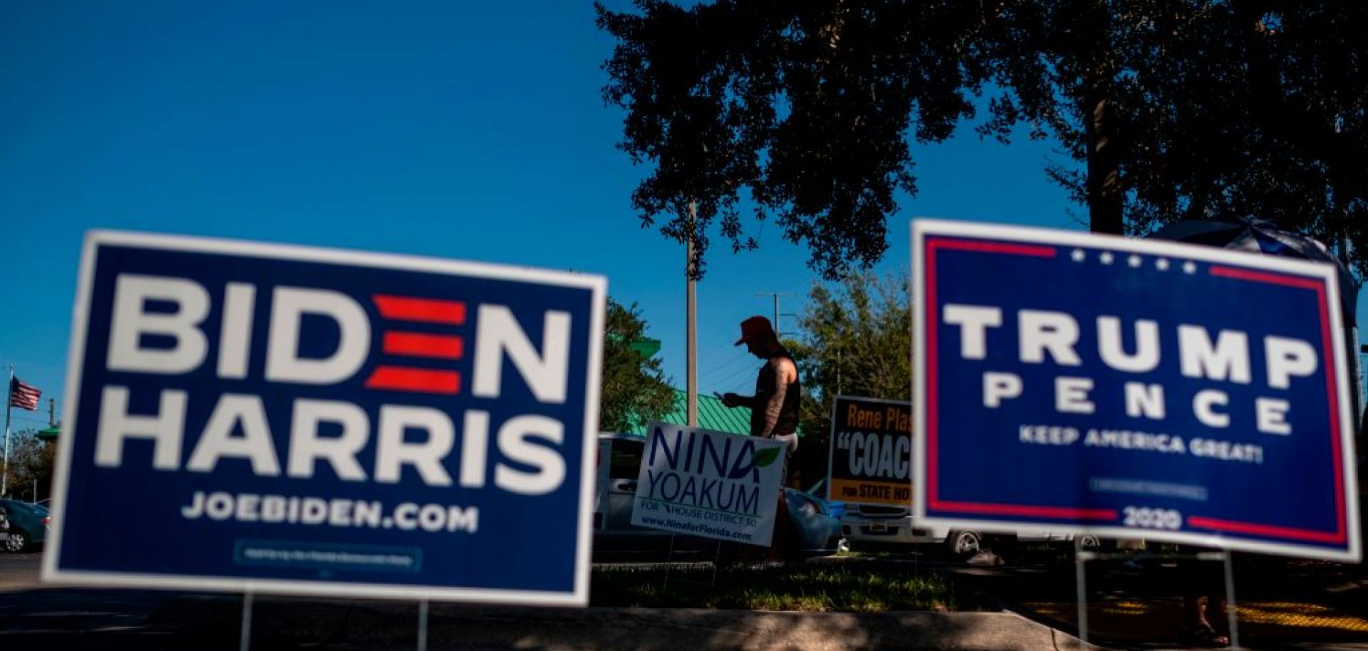 Biden and Trump campaign signs are displayed as voters line up to cast their ballots during early voting Oct. 30, 2020, at the Alafaya Branch Library in Orlando, Florida. 