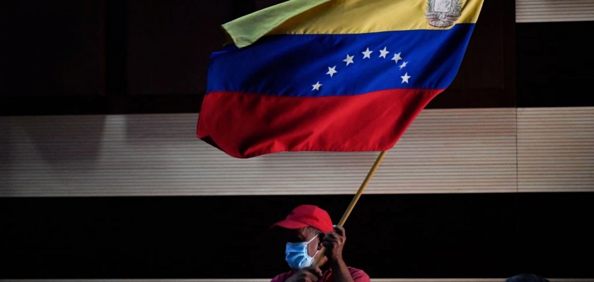 A supporter of the ruling United Socialist Party of Venezuela waves the flag of Venezuela on Jan. 10, 2022, in Barinas, Venezuela.